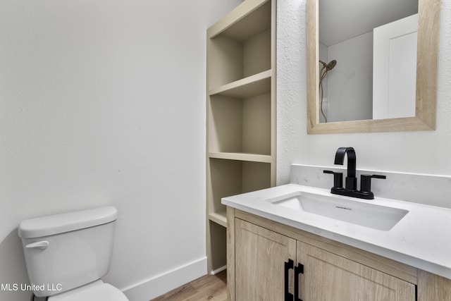 bathroom featuring wood-type flooring, toilet, and vanity