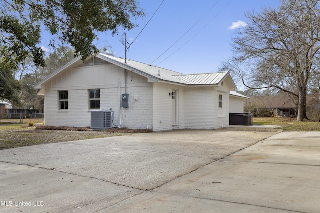 back of house featuring cooling unit and a hot tub