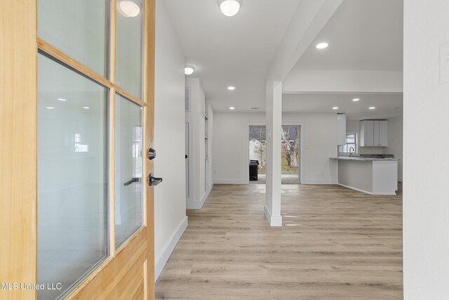 corridor featuring sink and light hardwood / wood-style flooring