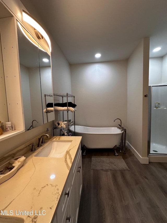 bathroom with a freestanding bath, recessed lighting, a shower stall, vanity, and wood finished floors