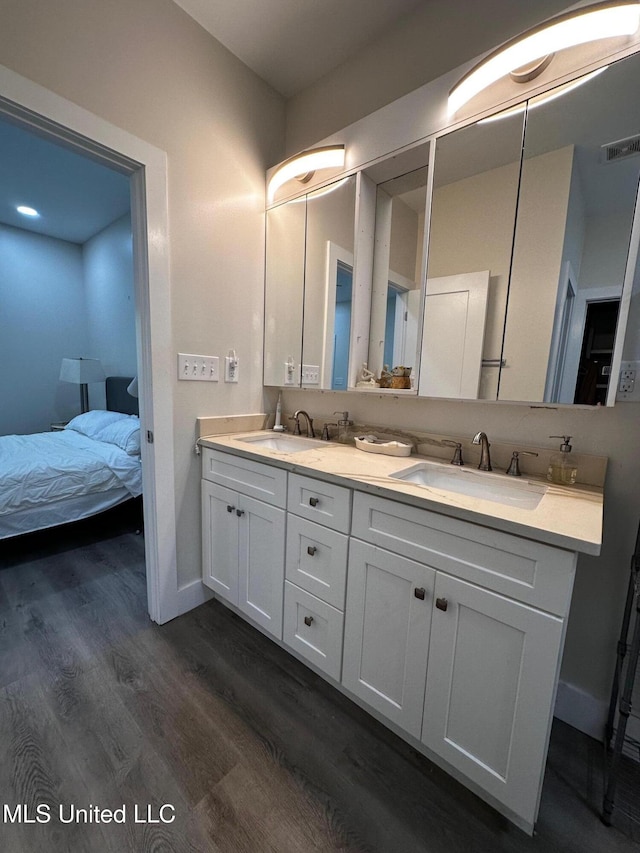 bathroom featuring double vanity, visible vents, a sink, and wood finished floors