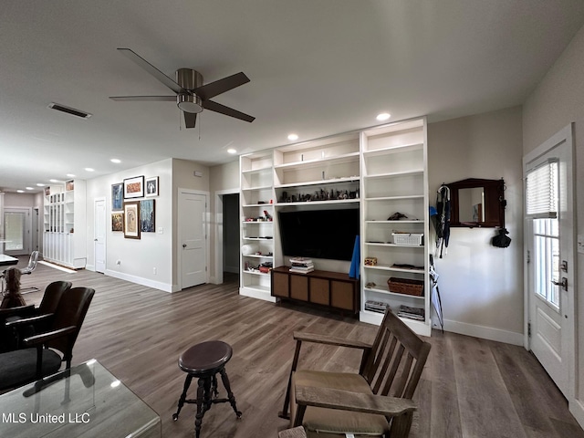 living room featuring wood finished floors, baseboards, a ceiling fan, and visible vents