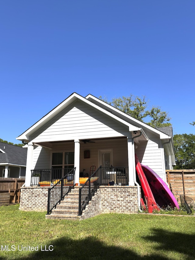 back of house featuring fence and a lawn