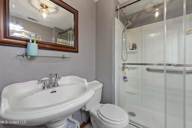 bathroom with sink, an enclosed shower, and toilet