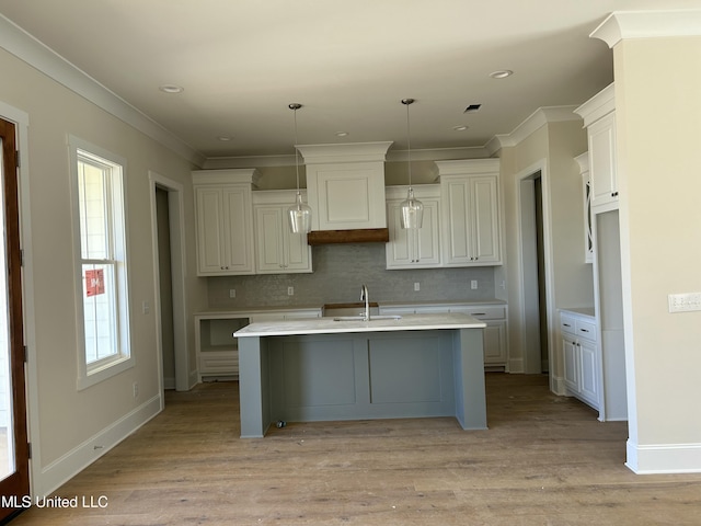 kitchen with light countertops, light wood-type flooring, backsplash, and a sink