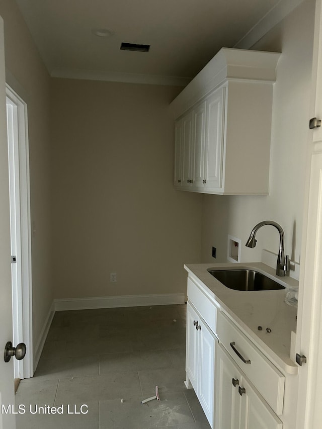 washroom featuring tile patterned floors, a sink, cabinet space, baseboards, and hookup for a washing machine