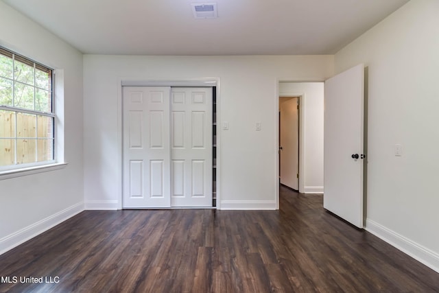 unfurnished bedroom with a closet and dark wood-type flooring