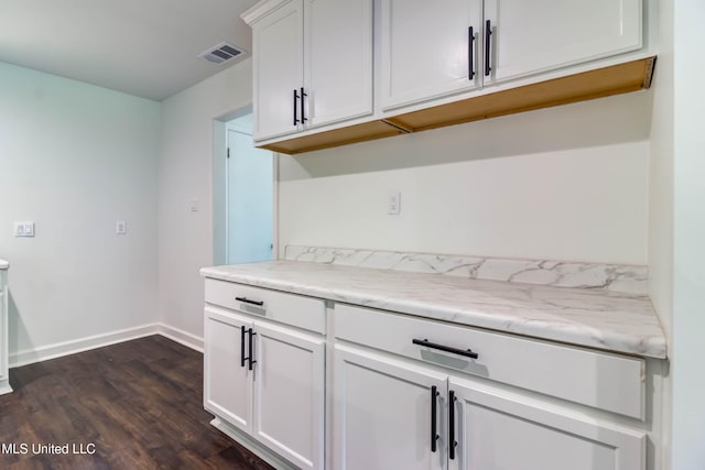 kitchen featuring light stone counters, dark hardwood / wood-style flooring, and white cabinets