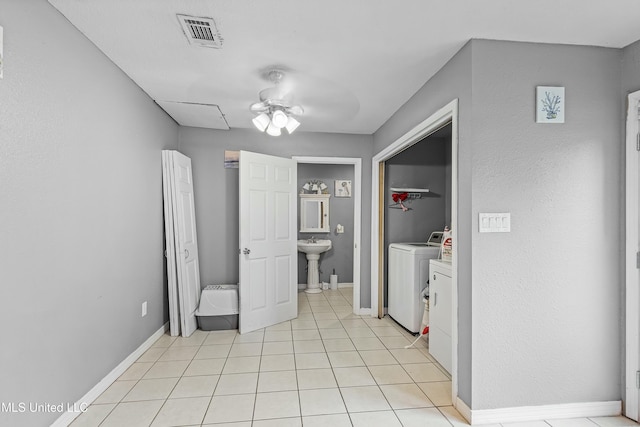 interior space with sink, light tile patterned floors, washing machine and dryer, and ceiling fan