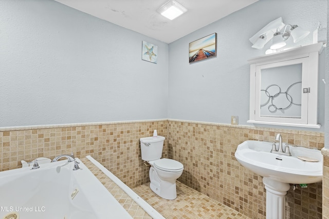 bathroom with tile walls, a bath, tile patterned floors, and toilet