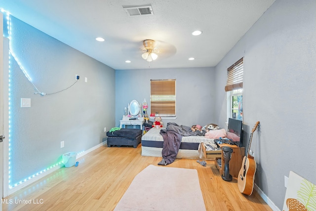 recreation room featuring wood-type flooring, a textured ceiling, and ceiling fan