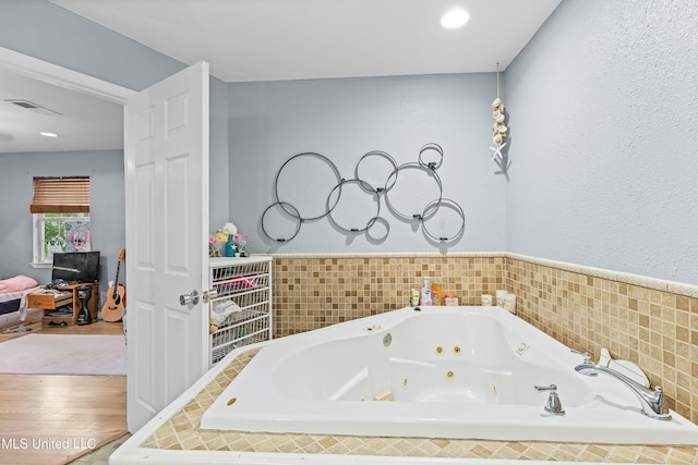 bathroom with wood-type flooring and tiled bath