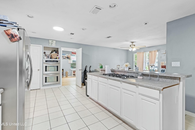 kitchen featuring white cabinetry, light tile patterned floors, ceiling fan, and appliances with stainless steel finishes