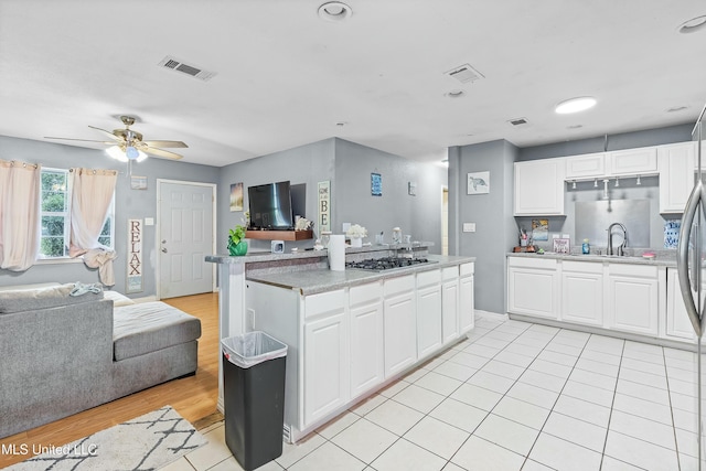 kitchen featuring white cabinetry, sink, stainless steel gas stovetop, and ceiling fan