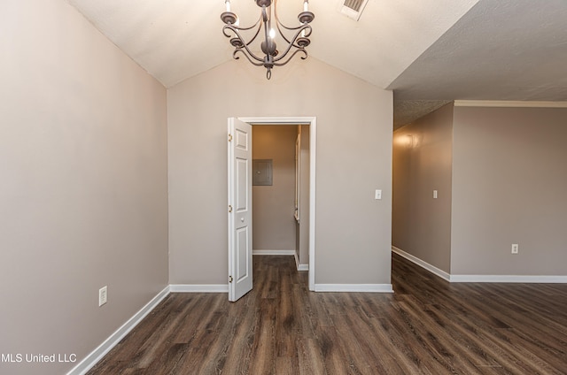 empty room with vaulted ceiling, ornamental molding, a textured ceiling, a notable chandelier, and dark hardwood / wood-style flooring