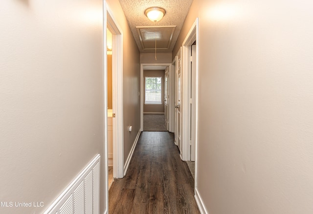 hall featuring a textured ceiling and dark wood-type flooring