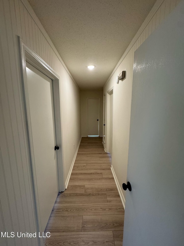 hall with light hardwood / wood-style flooring and a textured ceiling