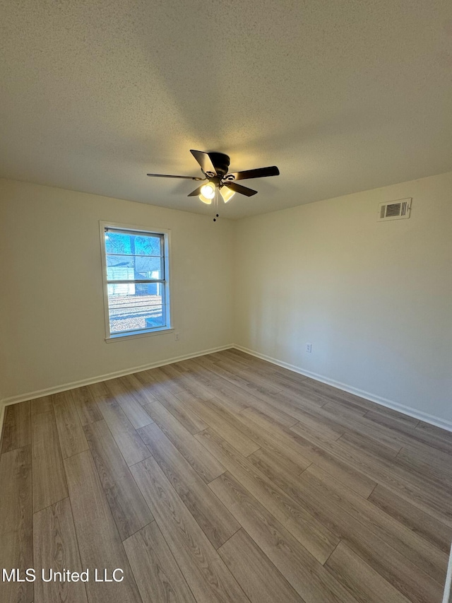 spare room featuring ceiling fan, light hardwood / wood-style floors, and a textured ceiling