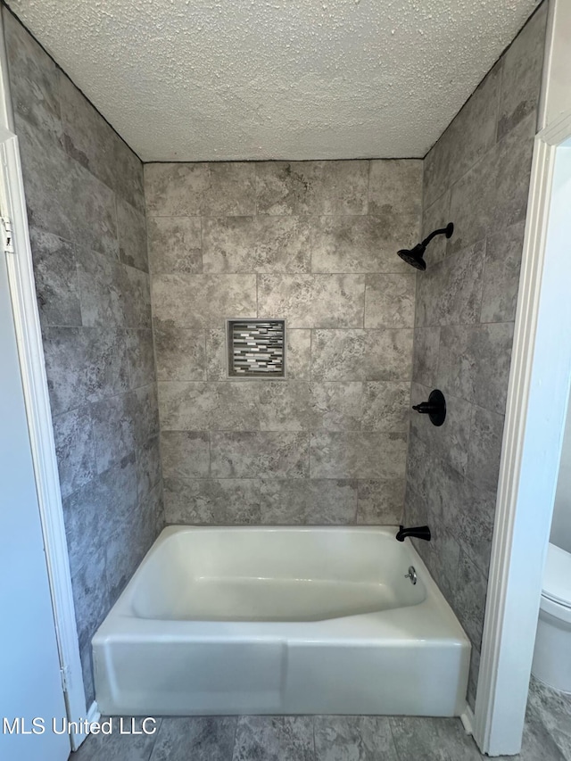 bathroom featuring toilet and tiled shower / bath combo