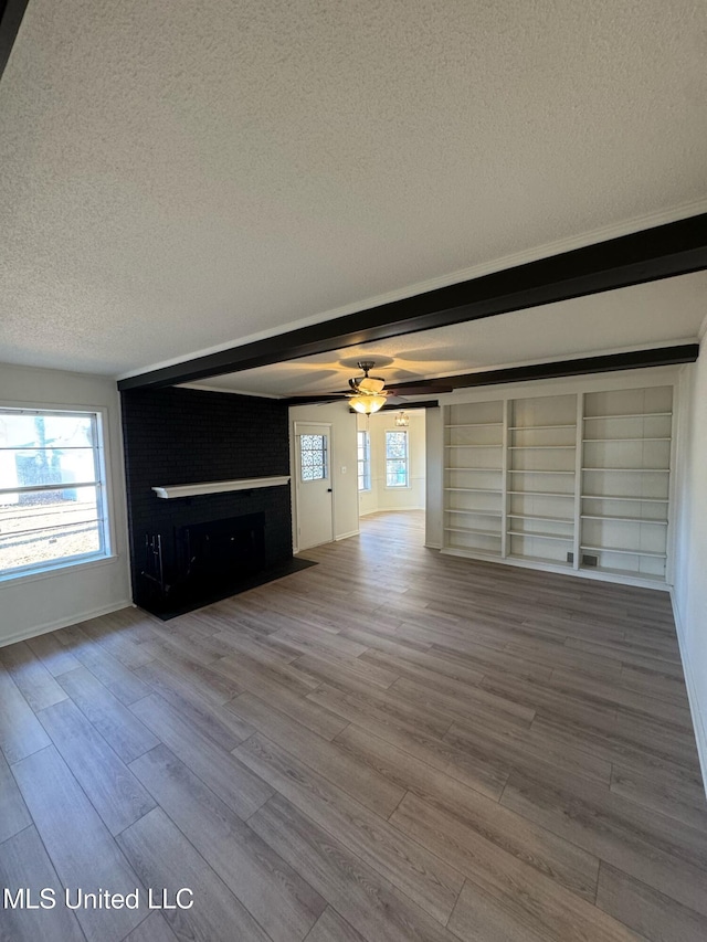 unfurnished living room with ceiling fan, hardwood / wood-style flooring, a large fireplace, and a textured ceiling