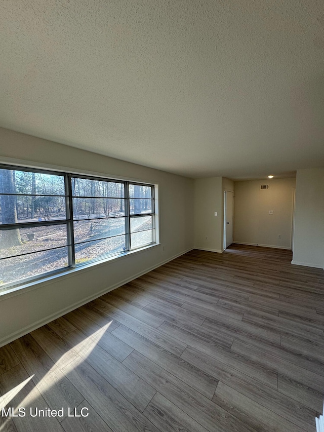 empty room with light hardwood / wood-style flooring and a textured ceiling