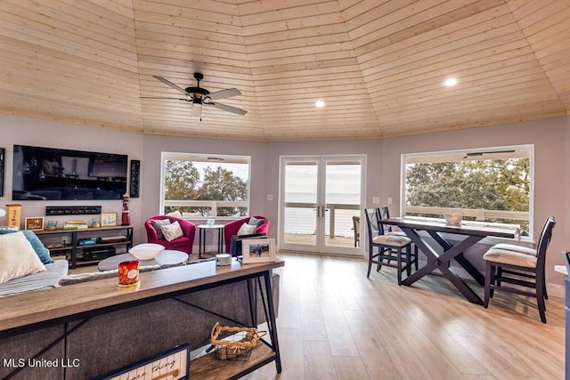 living room with ceiling fan, light hardwood / wood-style flooring, and a high ceiling