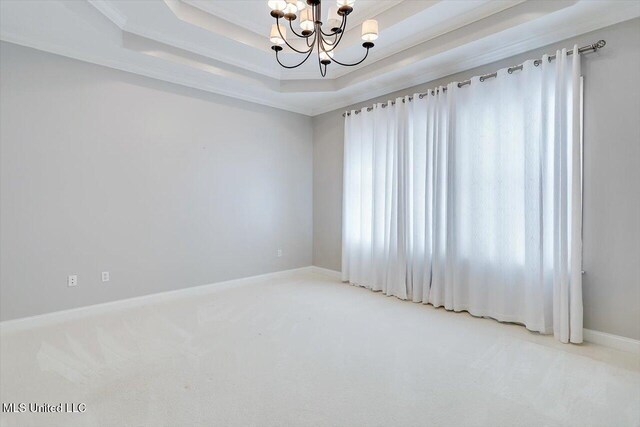 spare room featuring carpet floors, a tray ceiling, an inviting chandelier, and ornamental molding