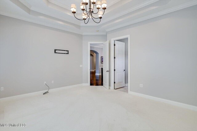 unfurnished room with light carpet, a tray ceiling, crown molding, and a notable chandelier