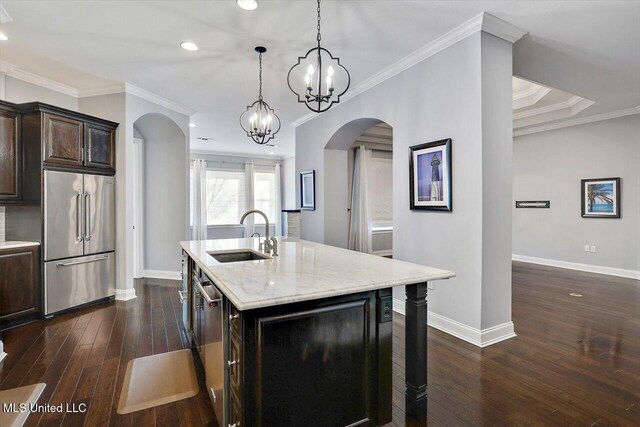 kitchen featuring stainless steel appliances, a kitchen island with sink, dark wood-type flooring, sink, and decorative light fixtures