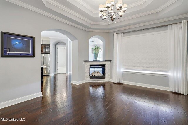 unfurnished living room featuring dark hardwood / wood-style flooring, a raised ceiling, crown molding, and a notable chandelier