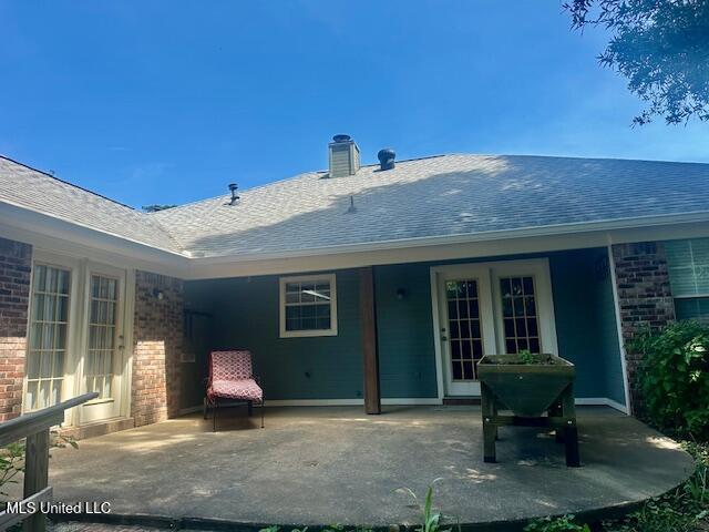 130 Eastwood Cir, Florence, MS 39073 - back of property featuring brick siding, a patio, roof with shingles, and a chimney