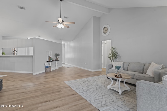 living room with ceiling fan, high vaulted ceiling, beam ceiling, and light hardwood / wood-style flooring