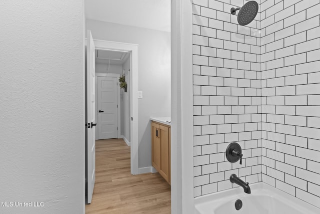 bathroom with tiled shower / bath, vanity, and wood-type flooring