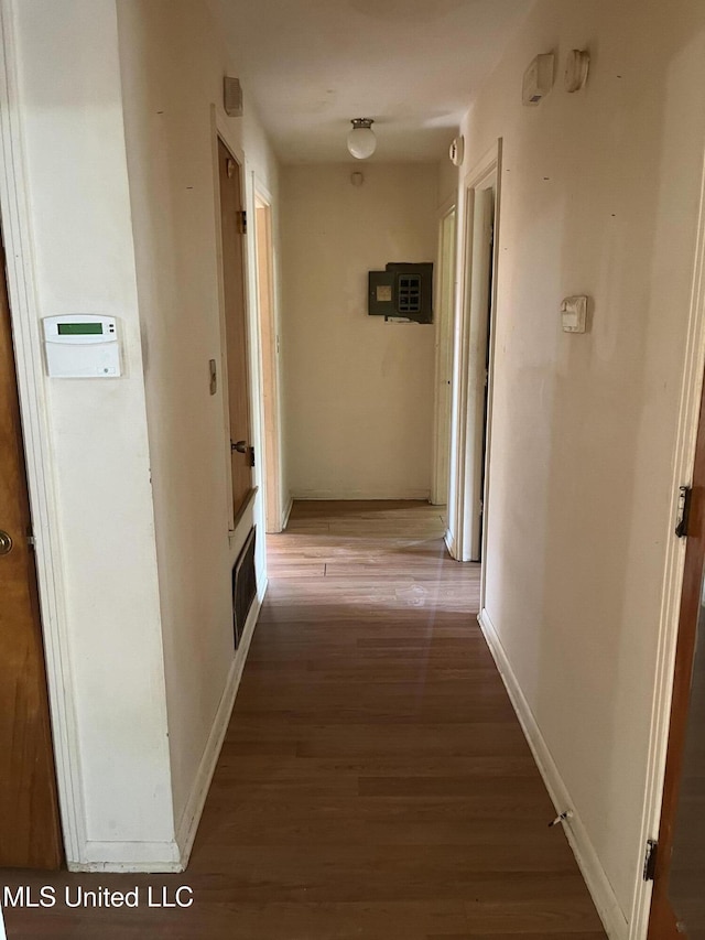 hall featuring baseboards, wood finished floors, and visible vents