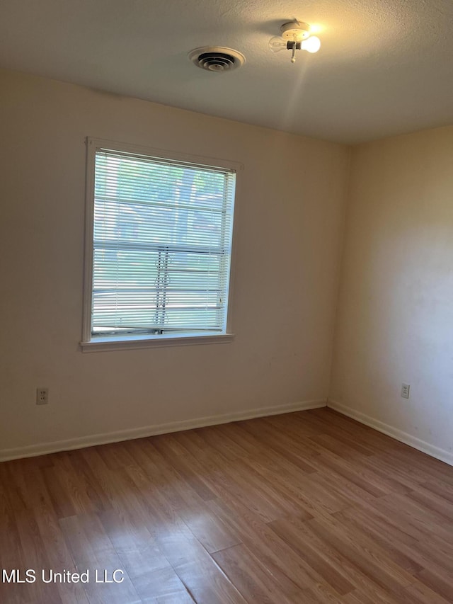 spare room with visible vents, baseboards, and wood finished floors