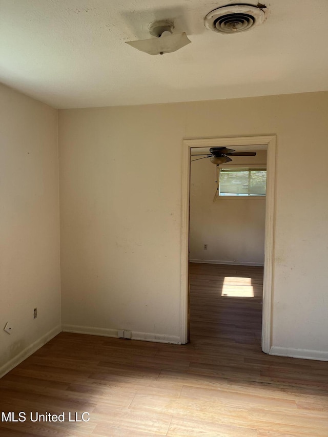spare room featuring visible vents, baseboards, and wood finished floors