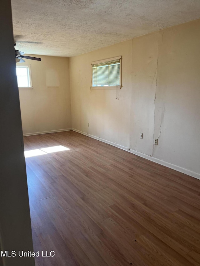 spare room with baseboards, a textured ceiling, ceiling fan, and wood finished floors