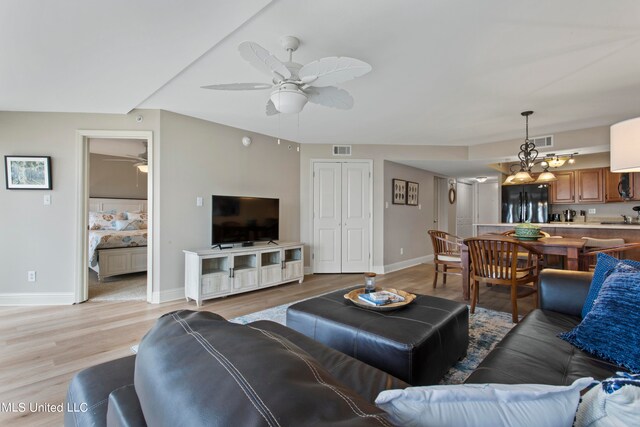 living room featuring sink, ceiling fan with notable chandelier, and light wood-type flooring