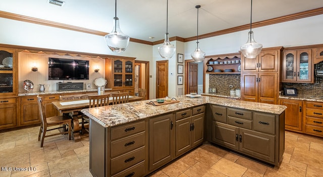 kitchen with light stone counters, hanging light fixtures, tasteful backsplash, and a center island