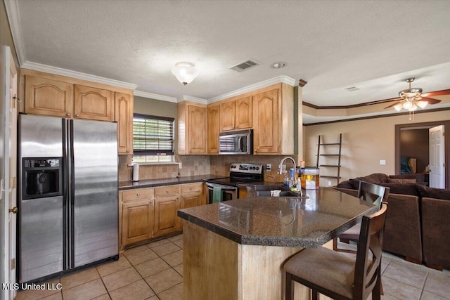 kitchen with appliances with stainless steel finishes, a sink, a peninsula, open floor plan, and a breakfast bar