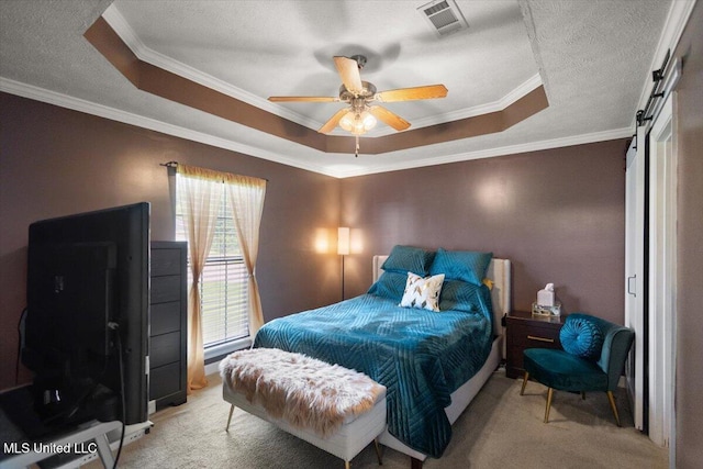 carpeted bedroom featuring a tray ceiling, a barn door, crown molding, and a ceiling fan