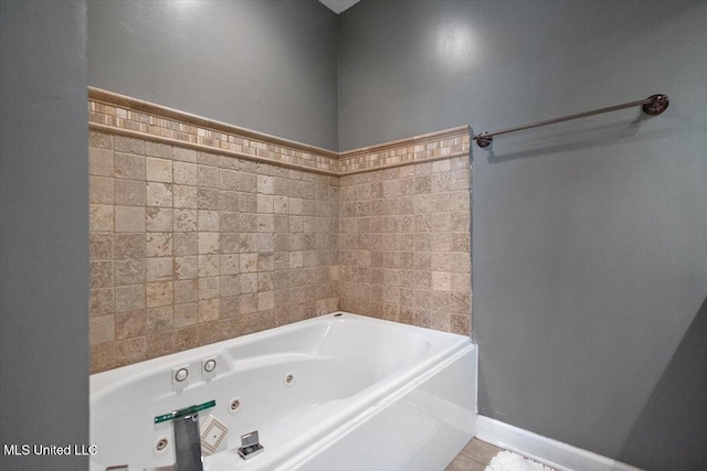 bathroom featuring a tub with jets and baseboards