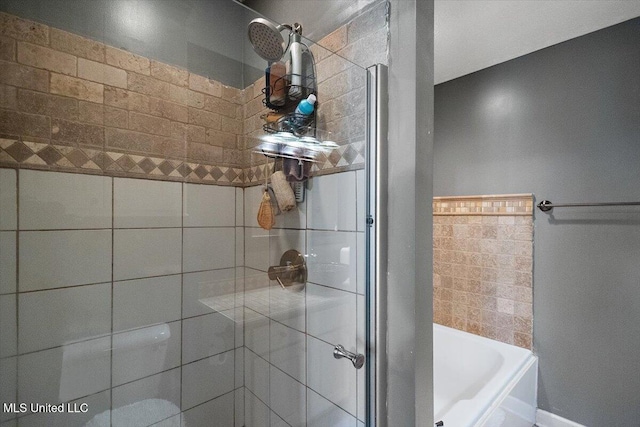 bathroom featuring a shower stall, a bath, and baseboards