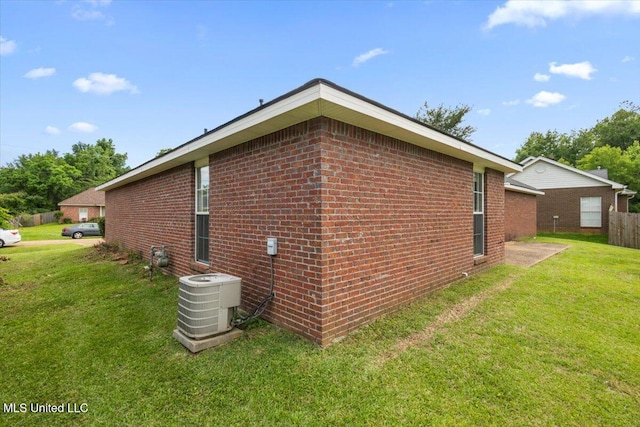 view of property exterior with central AC unit, brick siding, and a yard