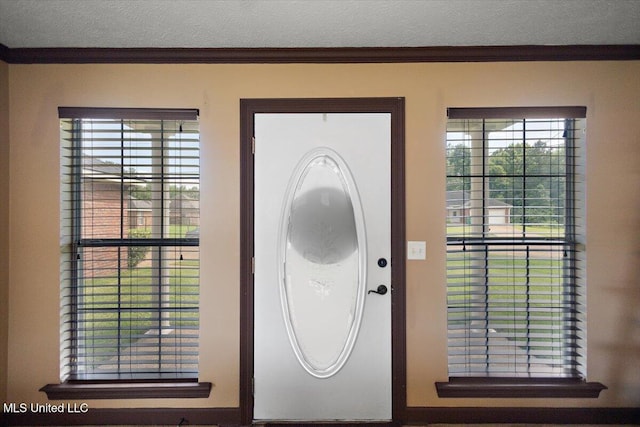 entryway featuring a textured ceiling, ornamental molding, and healthy amount of natural light