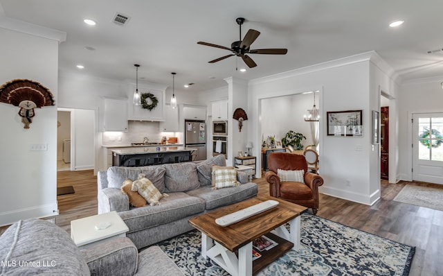 living room with sink, ceiling fan with notable chandelier, ornamental molding, and dark hardwood / wood-style floors