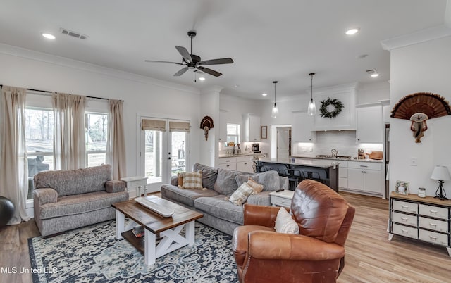 living room with light hardwood / wood-style flooring, ornamental molding, french doors, and ceiling fan