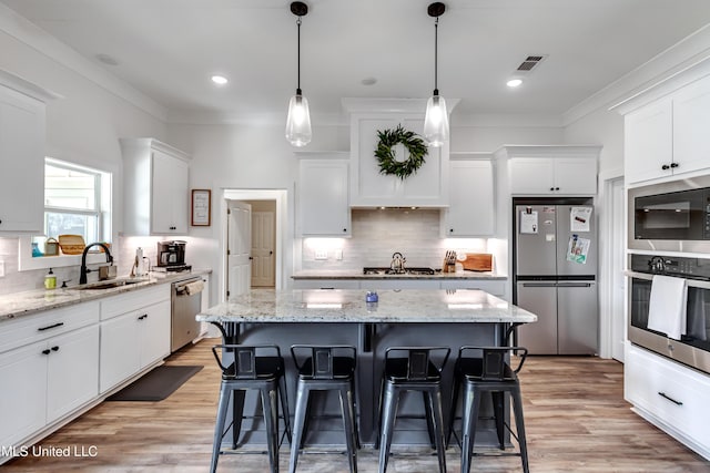 kitchen featuring appliances with stainless steel finishes, a center island, sink, and white cabinets