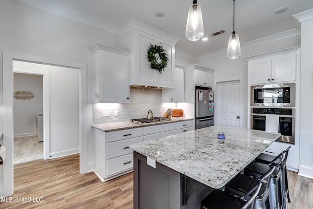 kitchen featuring a kitchen island, a breakfast bar, white cabinets, and appliances with stainless steel finishes