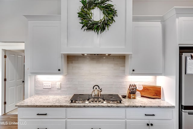 kitchen featuring backsplash, stainless steel appliances, light stone countertops, and white cabinets